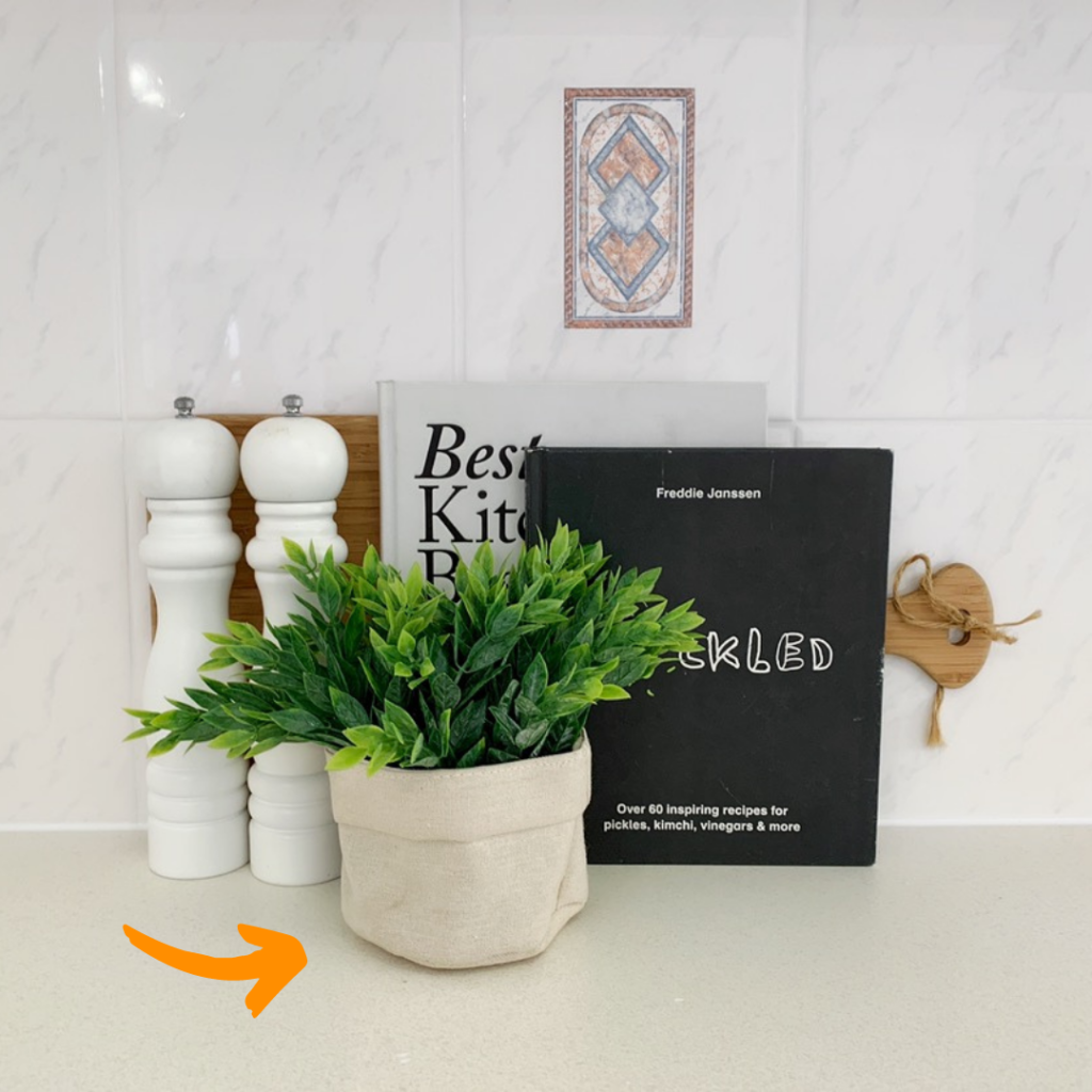 kitchen bench with two salt shakers, two cooking books and a small pot of plant in front