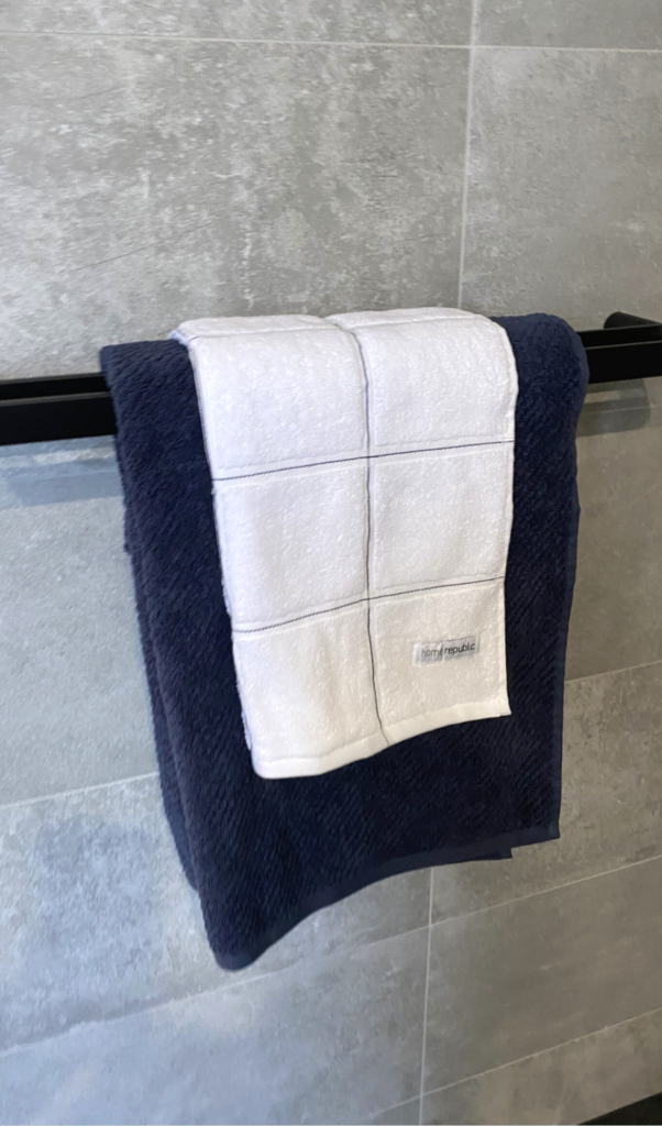 blue bath towel with a white patterned hand towel on top