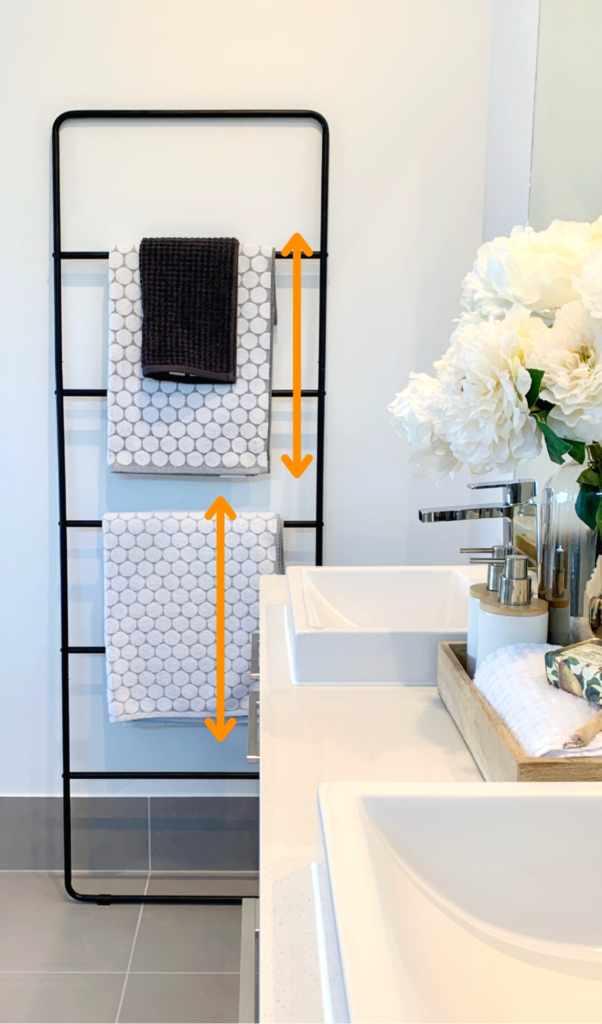 towel rack with two grey and white bath towels and a small dark hand towel overlapping