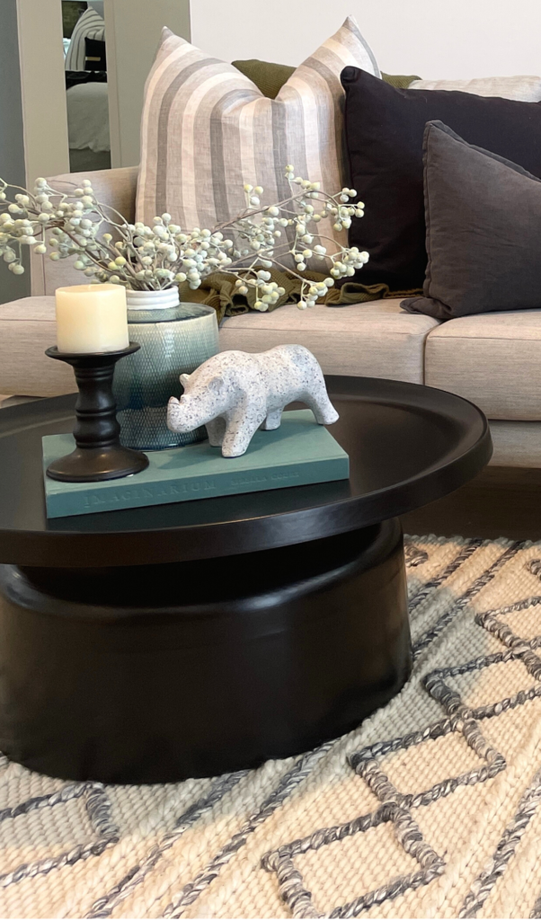dusty green book styled with a dusty green vase, statue of a rhinoceros on a coffee table