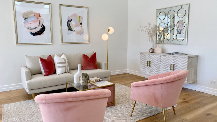 velvet pink armchairs with a sofa, pink abstract artwork on the wall and a white and golden buffet with decorations