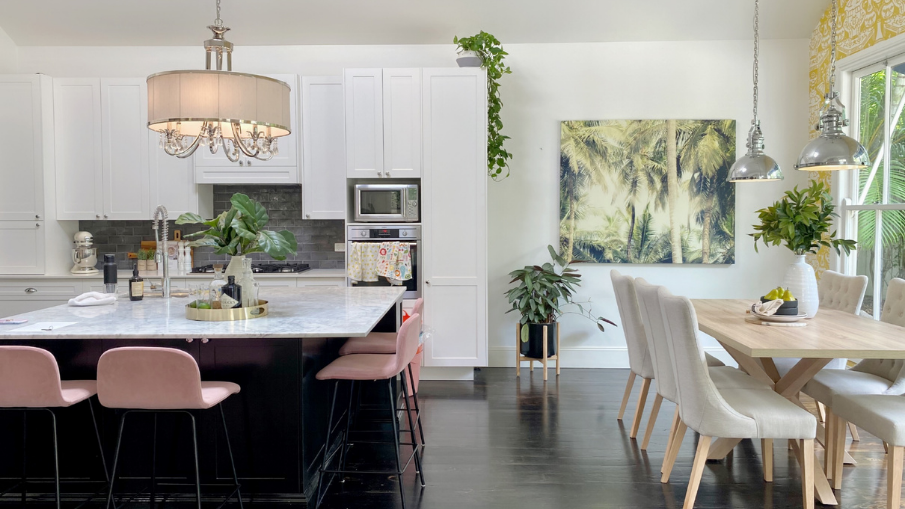black kitchen island with white marble top and pastel pink bar stools around it